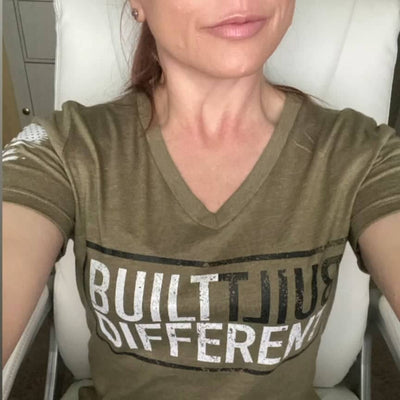 Person wearing a green t-shirt with 'BUILT DIFFERENT' text in a vehicle.