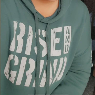 Person wearing a green hoodie with text, sitting indoors.