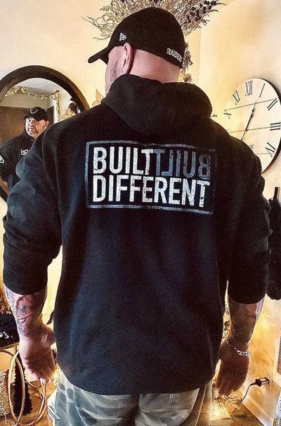 Man wearing Built Different back design heavyweight solid black hoodie
