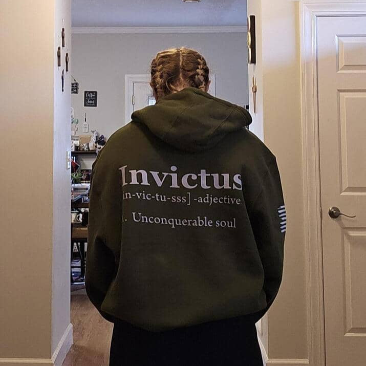 Person wearing a hoodie with 'Invictus' branding in a room.