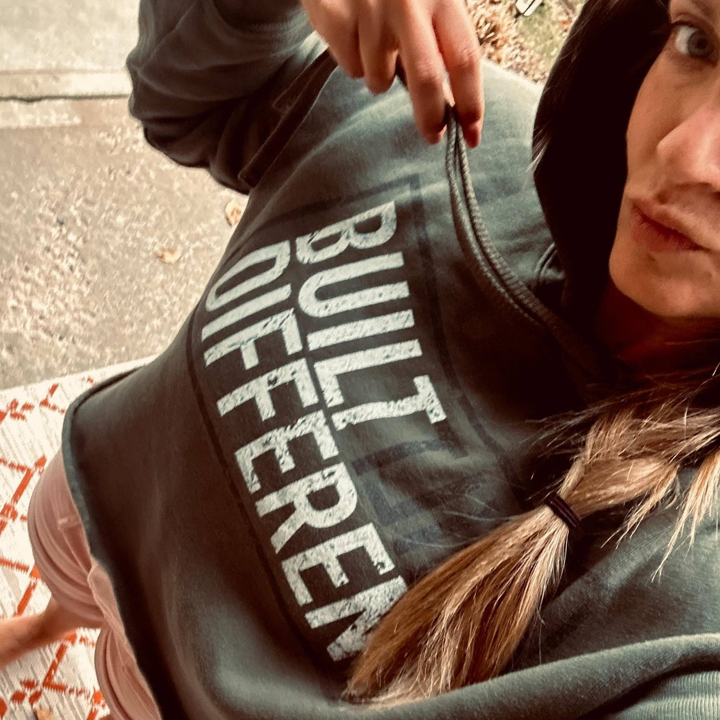 Person wearing a hoodie with 'BUILT DIFFERENT' text, standing on a patterned rug.
