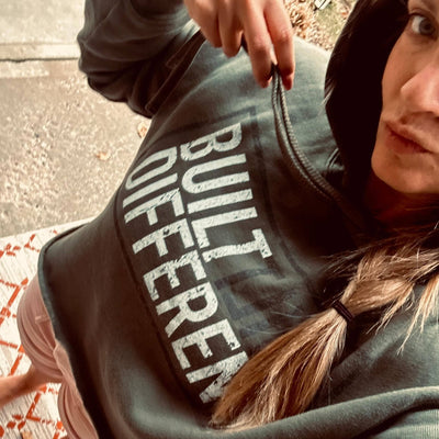 Person wearing a hoodie with 'BUILT DIFFERENT' text, standing on a patterned rug.