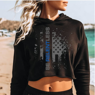 Person wearing a black hoodie with 'Be Relentless' text on a beach