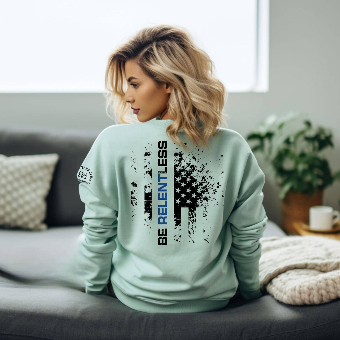 Woman wearing a light blue sweatshirt with text and graphics in a living room setting