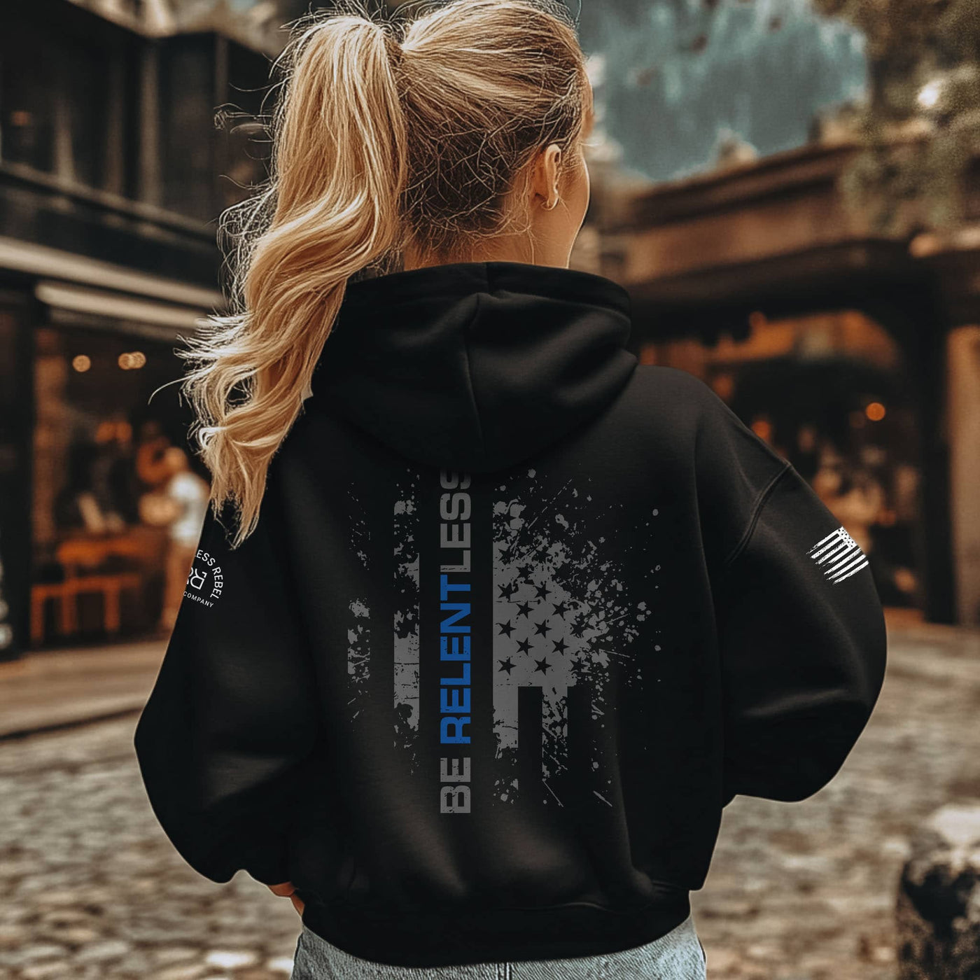 Person wearing a black hoodie with text and graphics, standing outdoors.