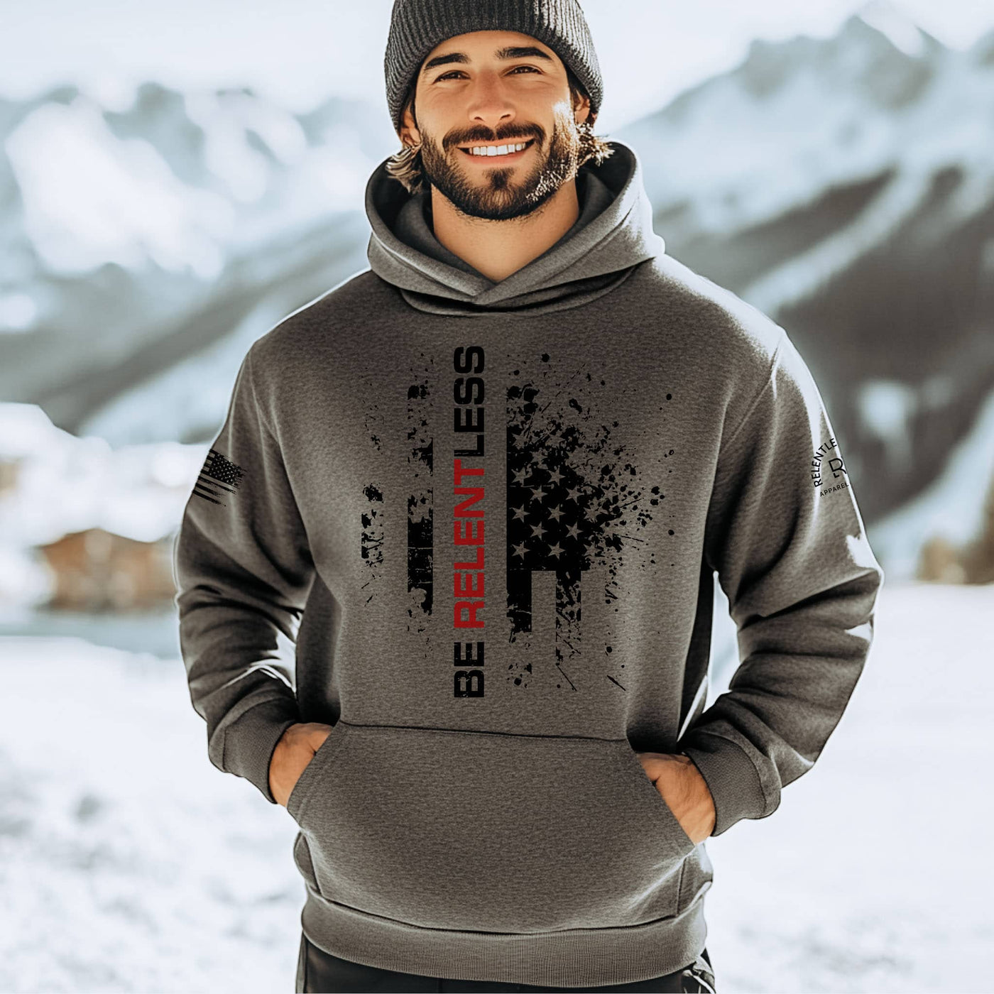 Man wearing a gray hoodie with text in a snowy mountain setting