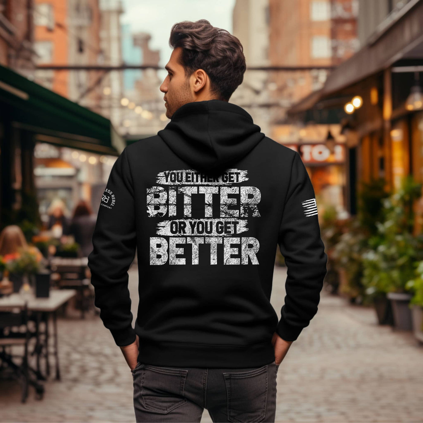 Man wearing a black hoodie with motivational text on the back in an urban setting
