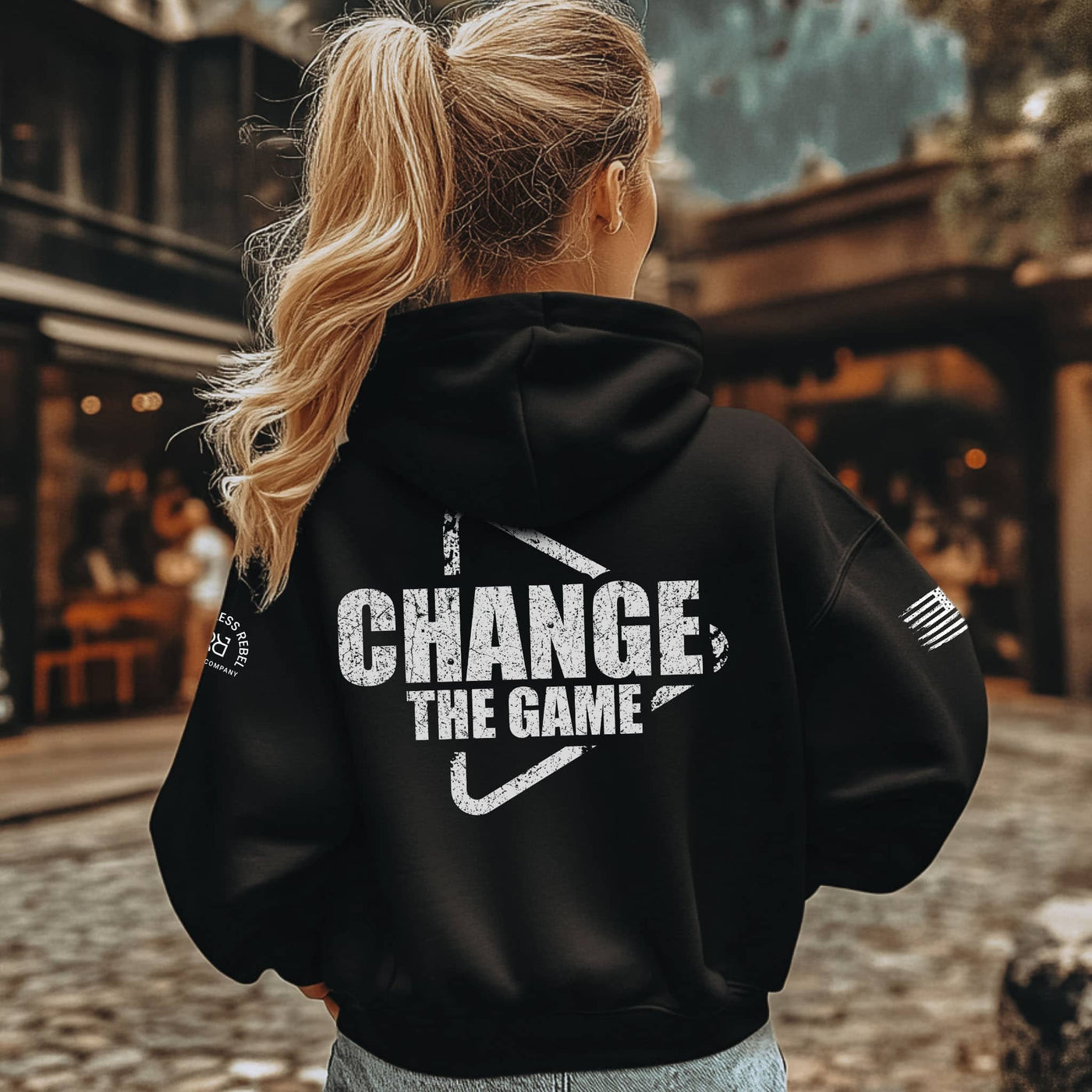 Person wearing a black hoodie with 'Change The Game' text on the back, standing outdoors.