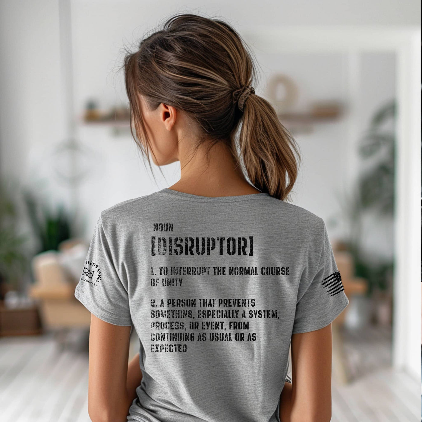 Person wearing a gray t-shirt with text on the back in a room setting