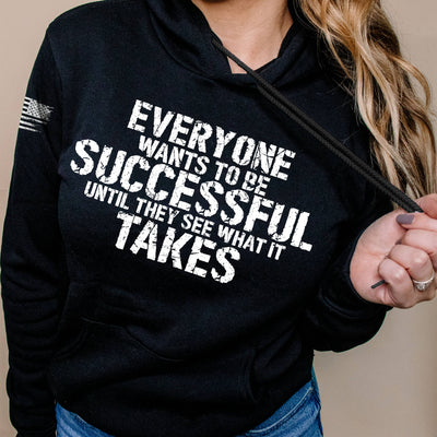 Person wearing a black hoodie with motivational quote on a beige background