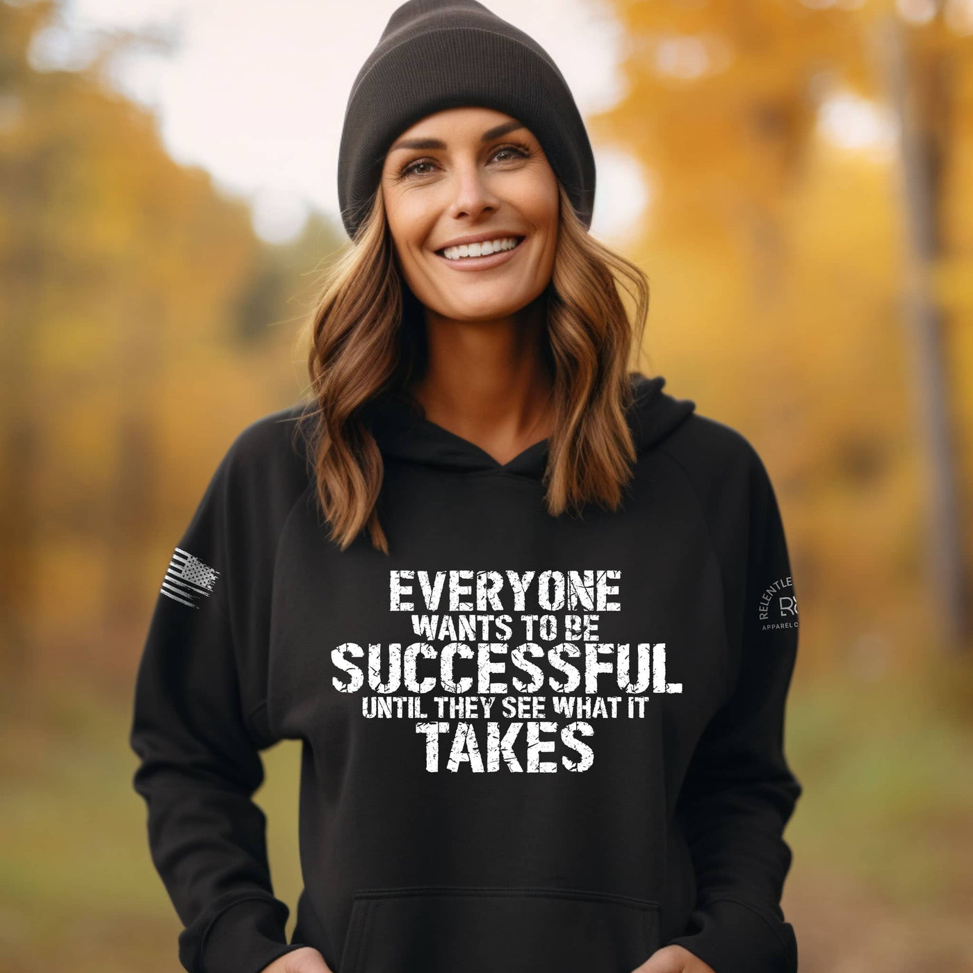 Woman wearing a black hoodie with a motivational quote in an autumn setting