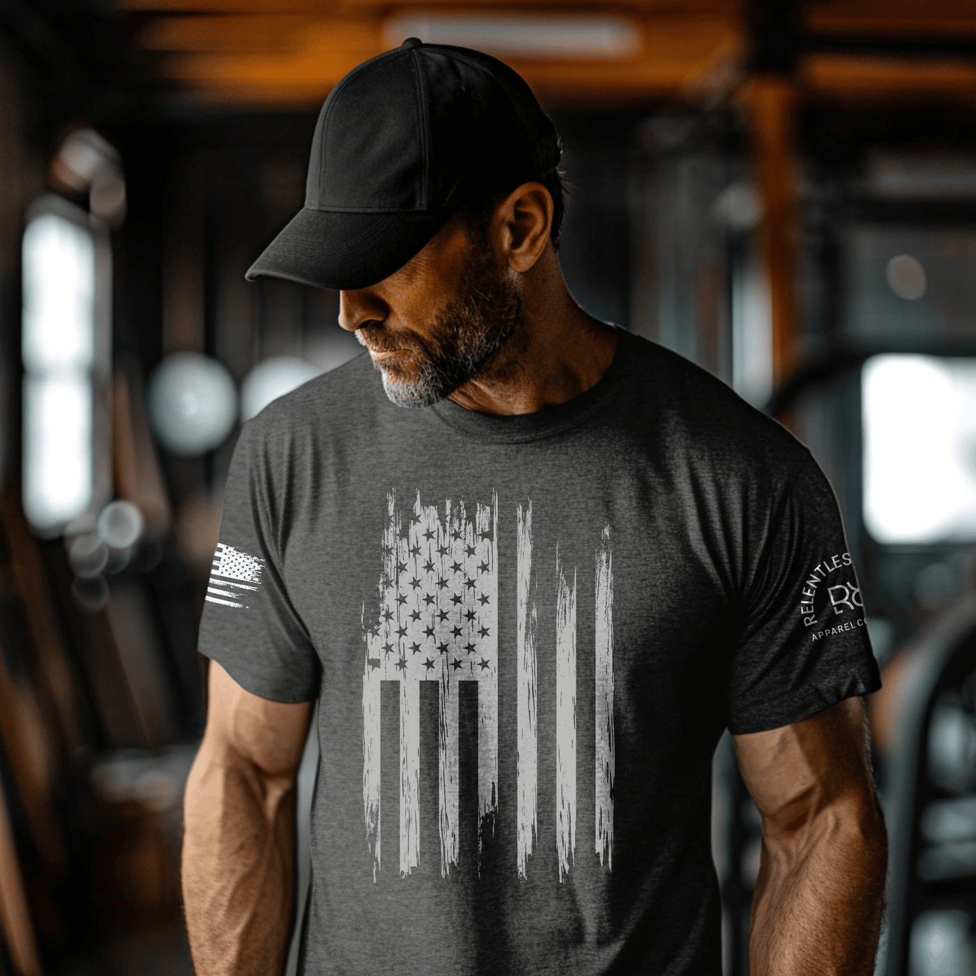 Man wearing a dark t-shirt with an American flag design in a gym setting