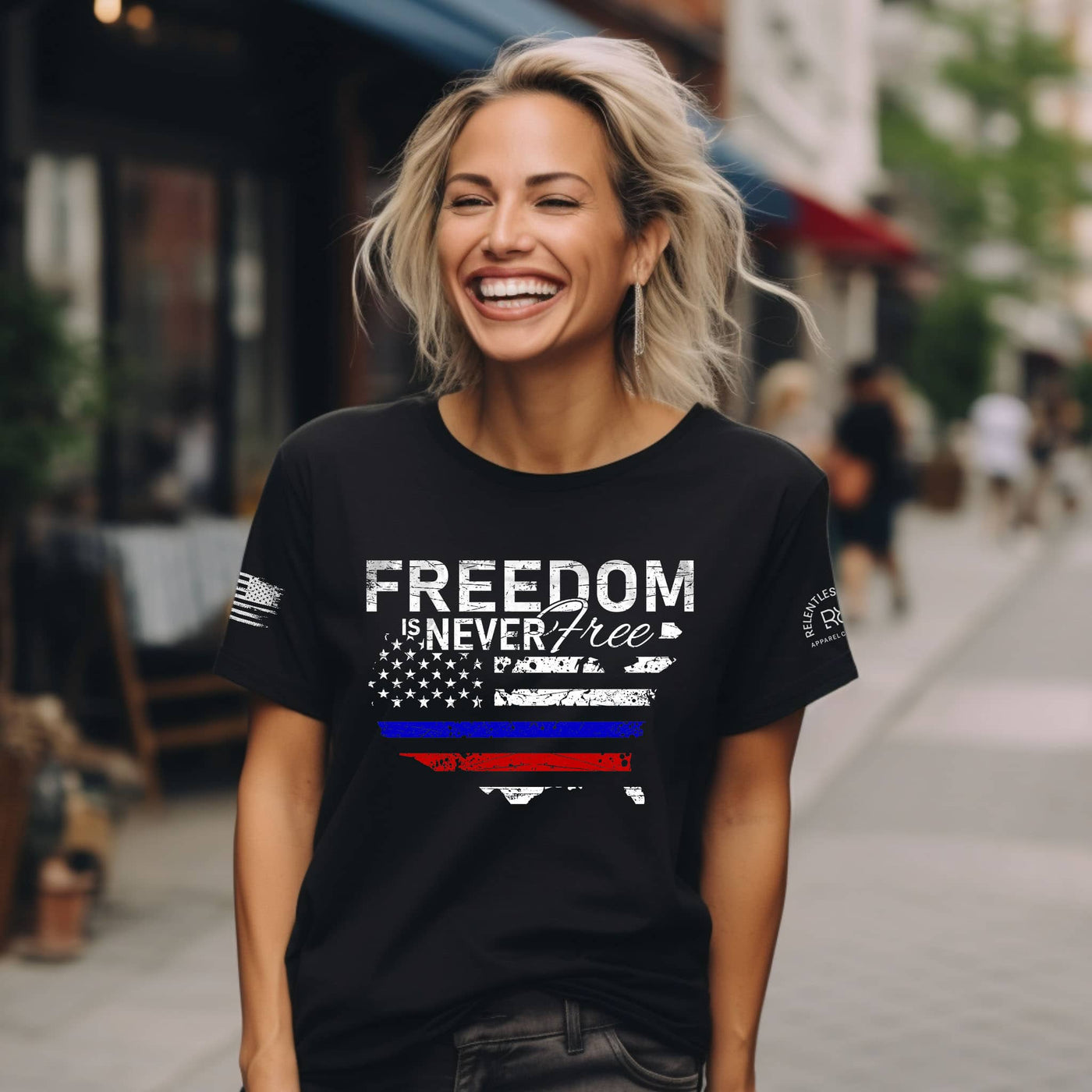 Woman wearing a black t-shirt with 'Freedom is Never Free' design on a city street.