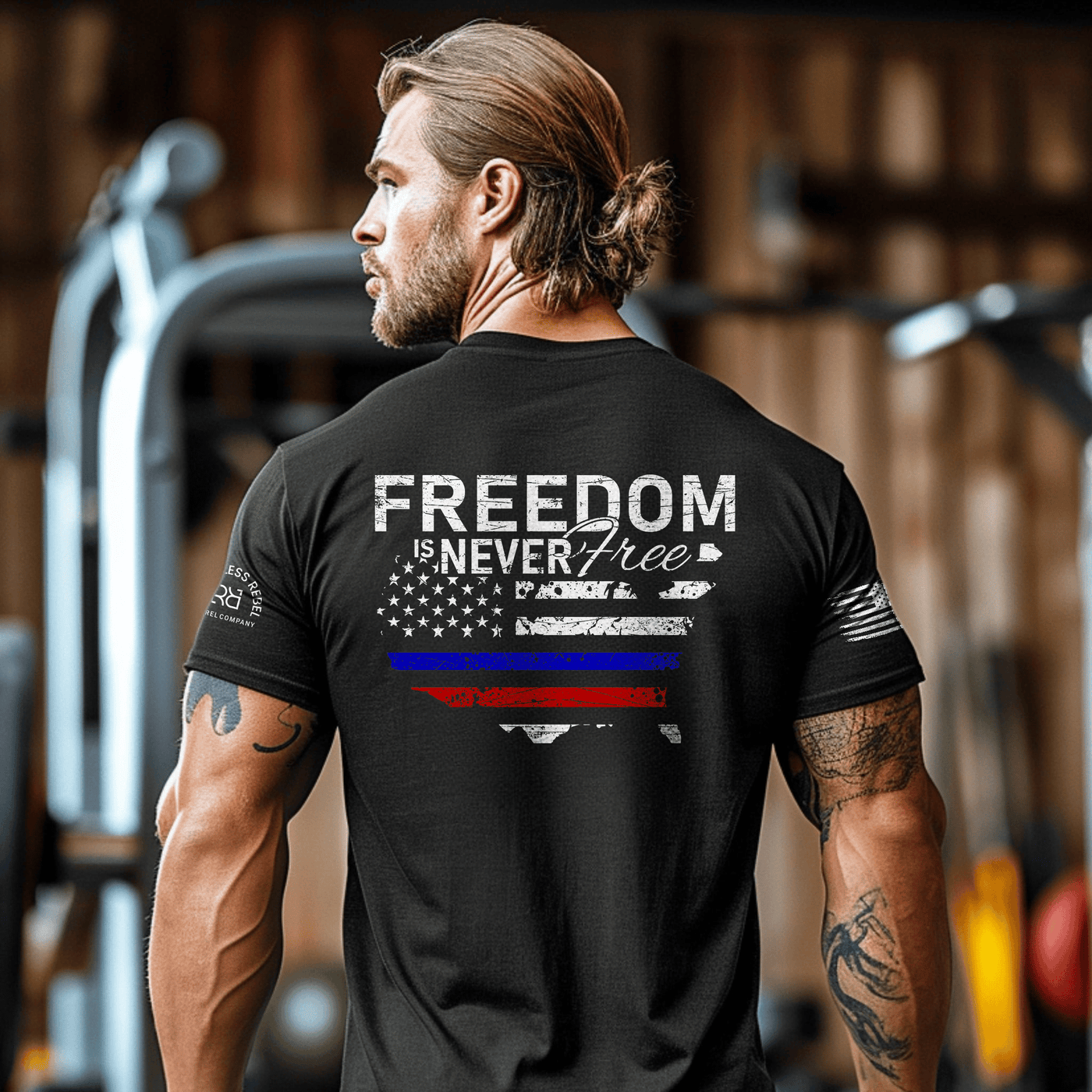 Man wearing a black t-shirt with 'Freedom is Never Free' design in a gym setting