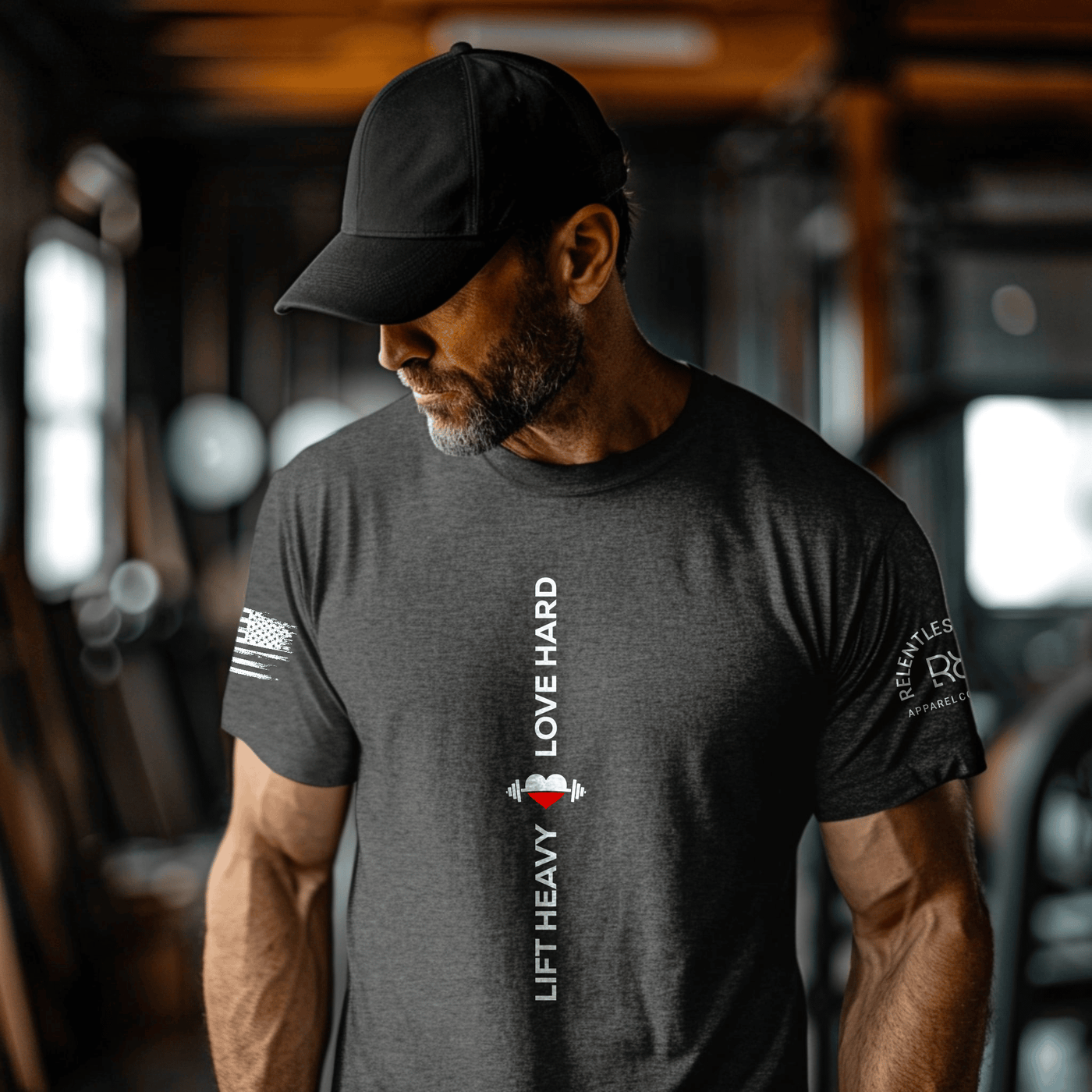 Man wearing a dark gray t-shirt with 'Lift Heavy' branding and text in a gym setting