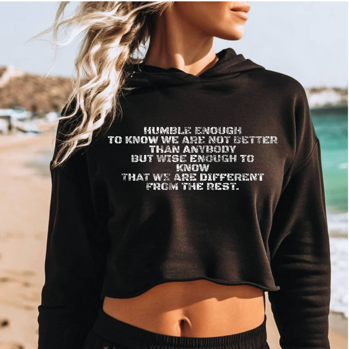 Person wearing a black hoodie with a motivational quote on a beach