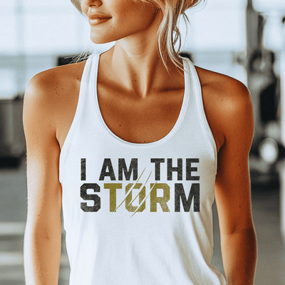 Woman wearing a white tank top with 'I AM THE STORM' text in a gym setting