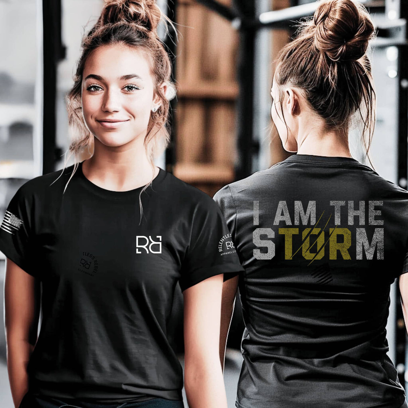 Woman wearing a black t-shirt with a logo on the front and 'I AM THE STORM' text on the back, standing in a gym setting.