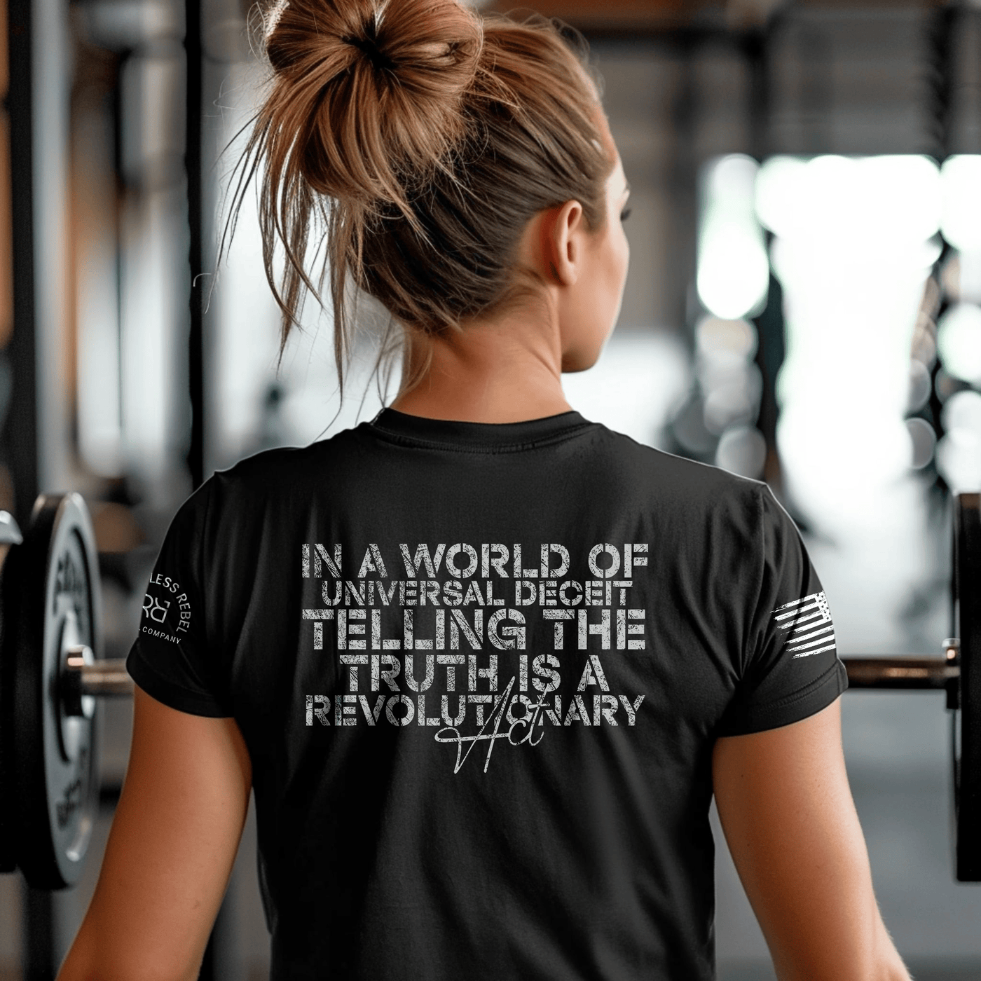 Person wearing a black t-shirt with a motivational quote in a gym setting