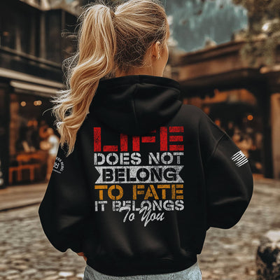 Person wearing a black hoodie with a motivational quote on the back, standing outdoors.