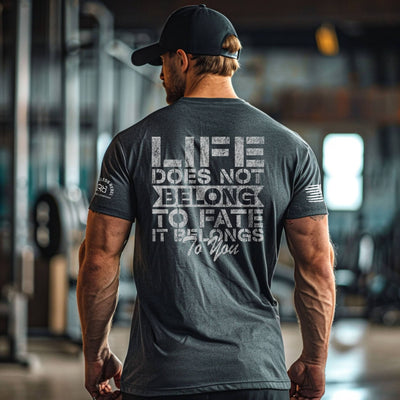 Man wearing a motivational t-shirt with text on the back in an indoor setting.