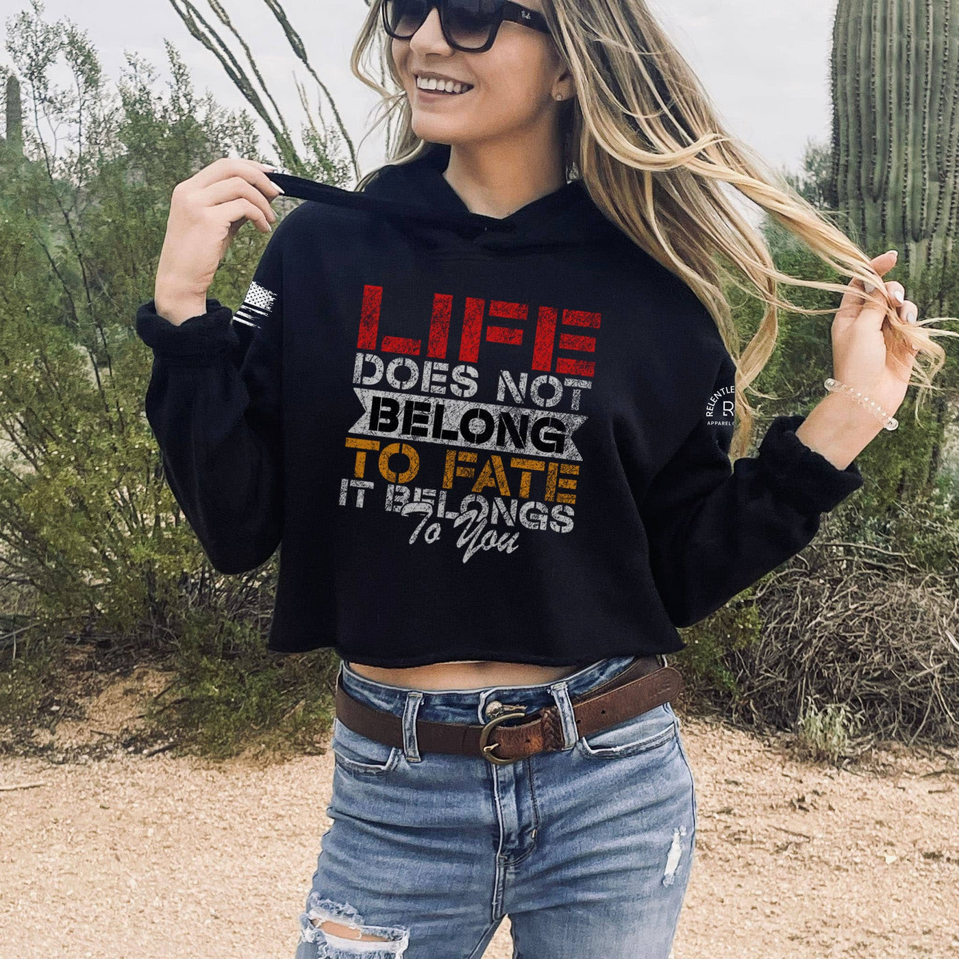 Woman wearing a black hoodie with a motivational quote in a desert setting