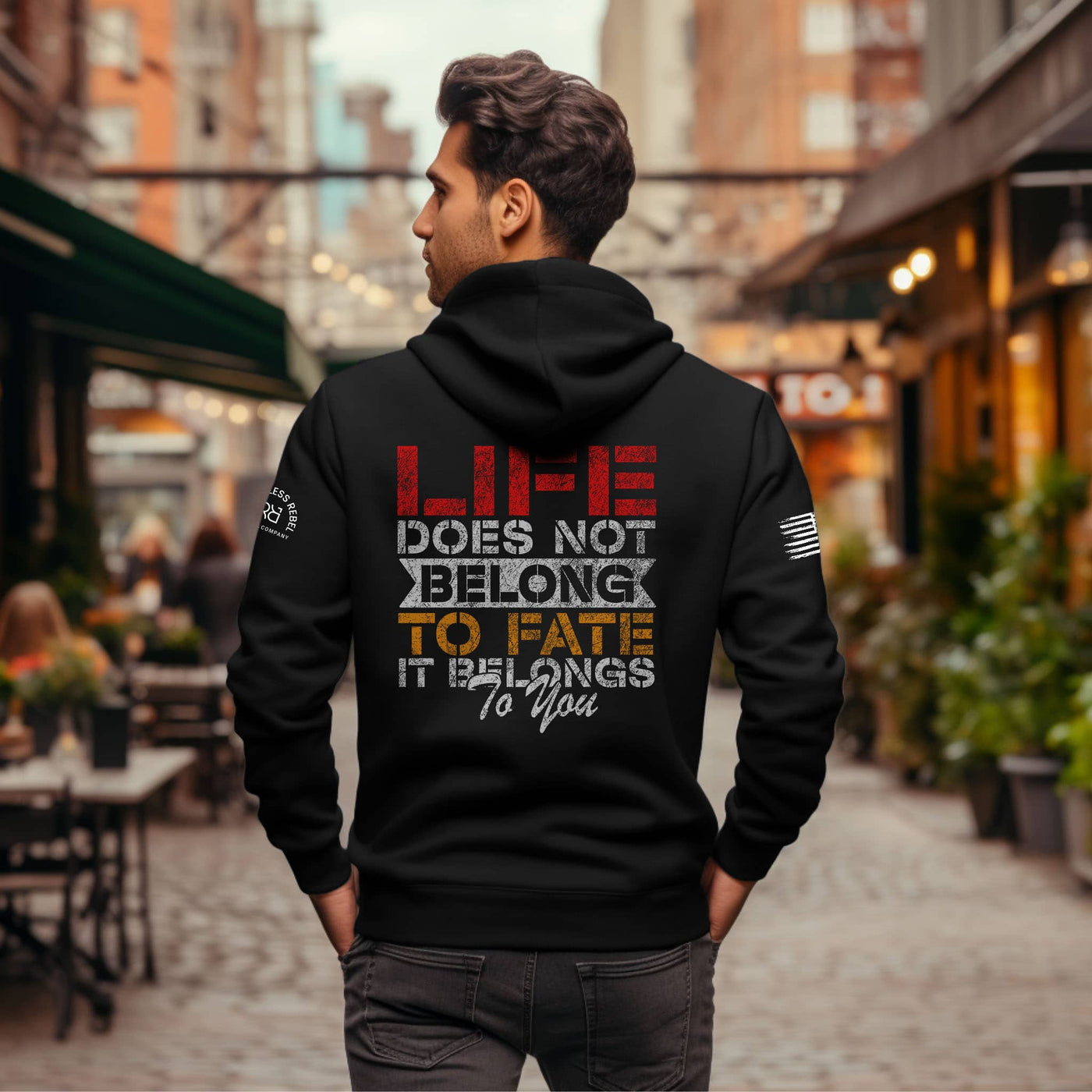 Person wearing a black hoodie with a motivational quote on the back in an urban setting.