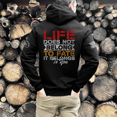Person wearing a black hoodie with a motivational quote against a background of stacked wooden logs.