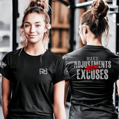 Woman wearing a black t-shirt with a logo on the front and motivational text on the back in a gym setting.