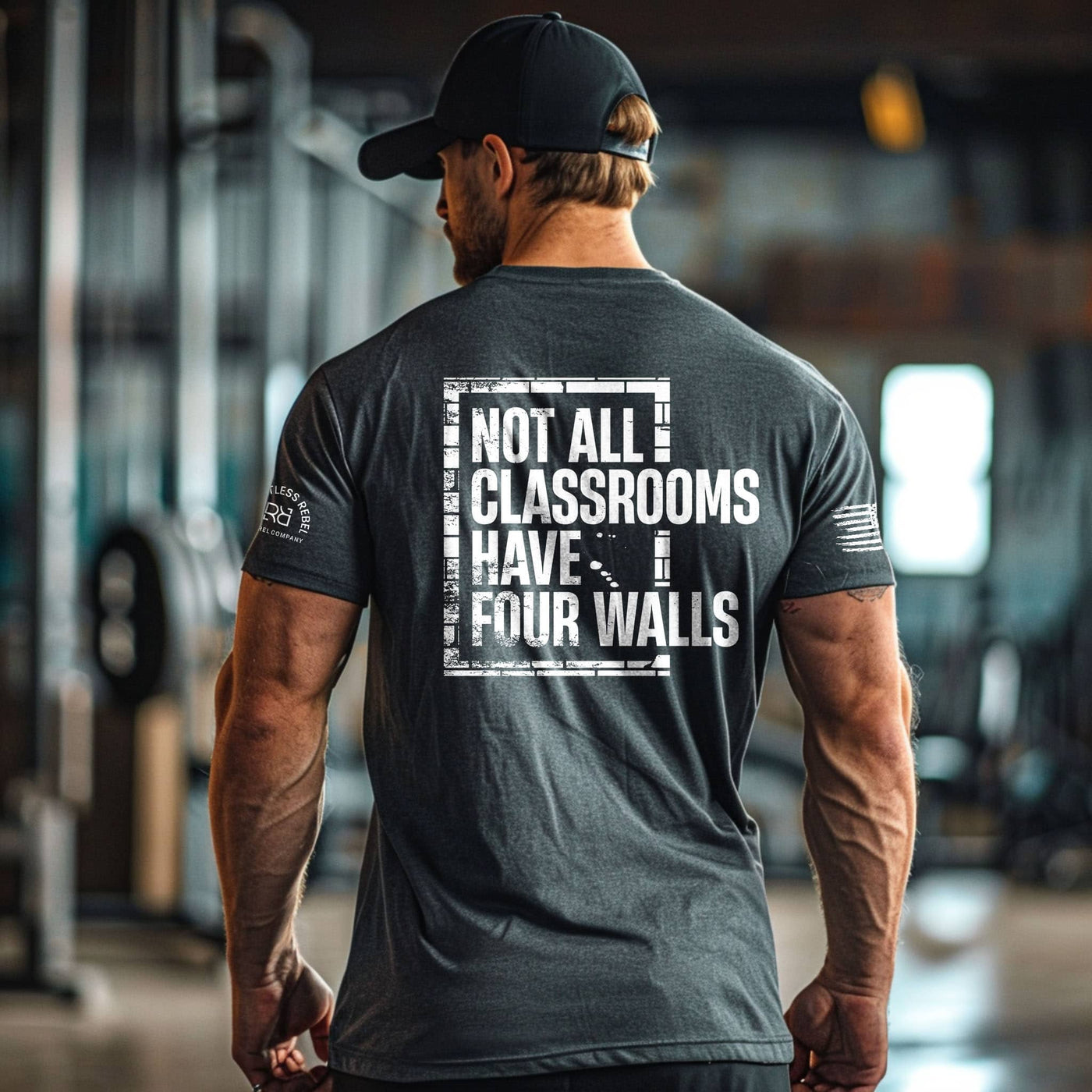 Man wearing a t-shirt with 'Not All Classrooms Have Four Walls' text in an indoor setting.
