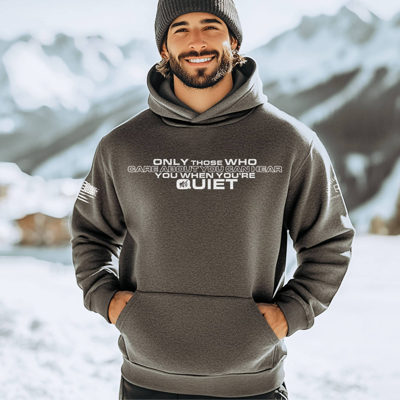 Man wearing a hoodie with text in a snowy mountain setting