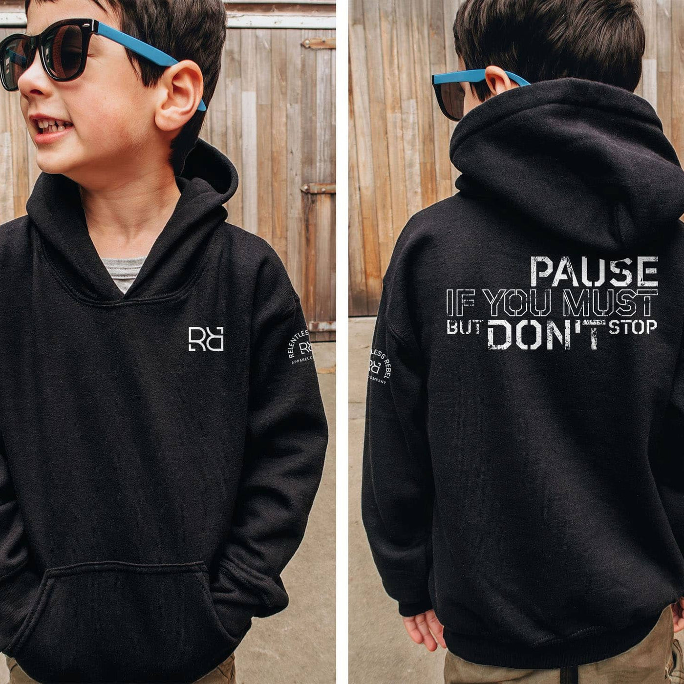 Child wearing a black hoodie with a logo on the front and text on the back, standing in front of a wooden fence.