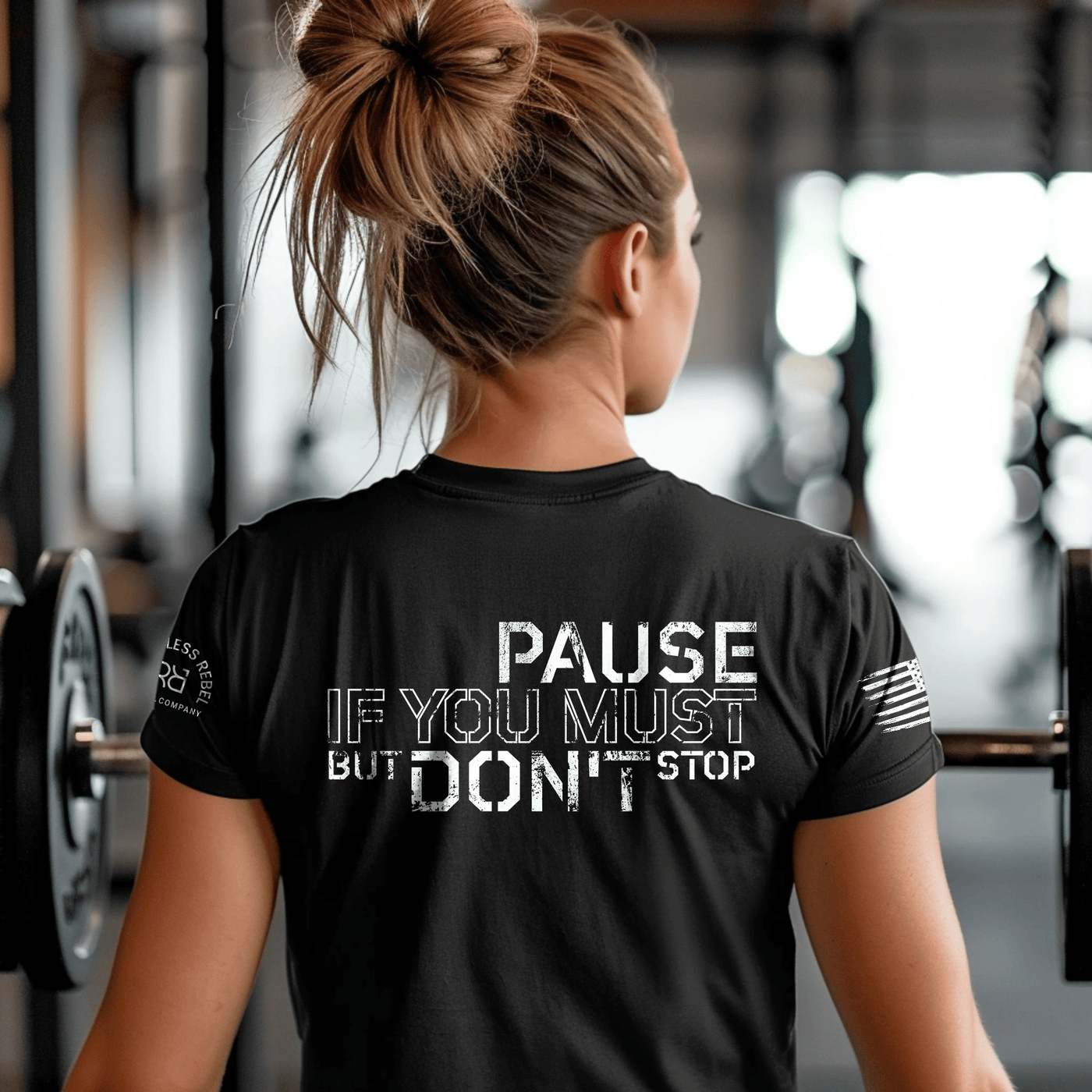 Person wearing a black t-shirt with motivational text in a gym setting