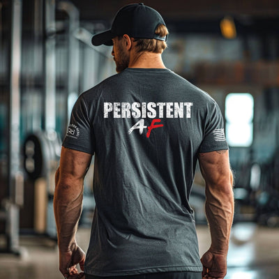 Man wearing a black t-shirt with 'PERSISTENT AF' text in an indoor setting