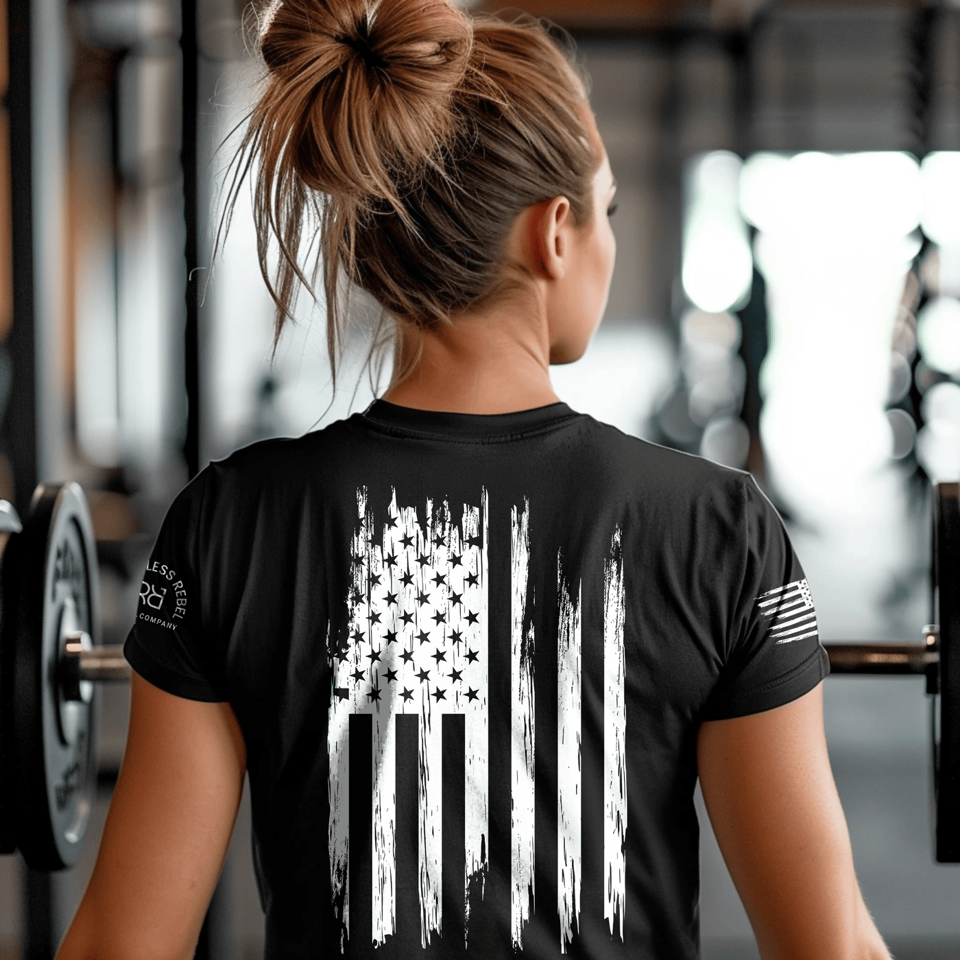 Person wearing a black t-shirt with an American flag design in a gym setting