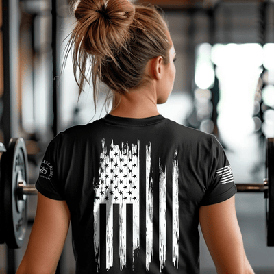Person wearing a black t-shirt with an American flag design in a gym setting