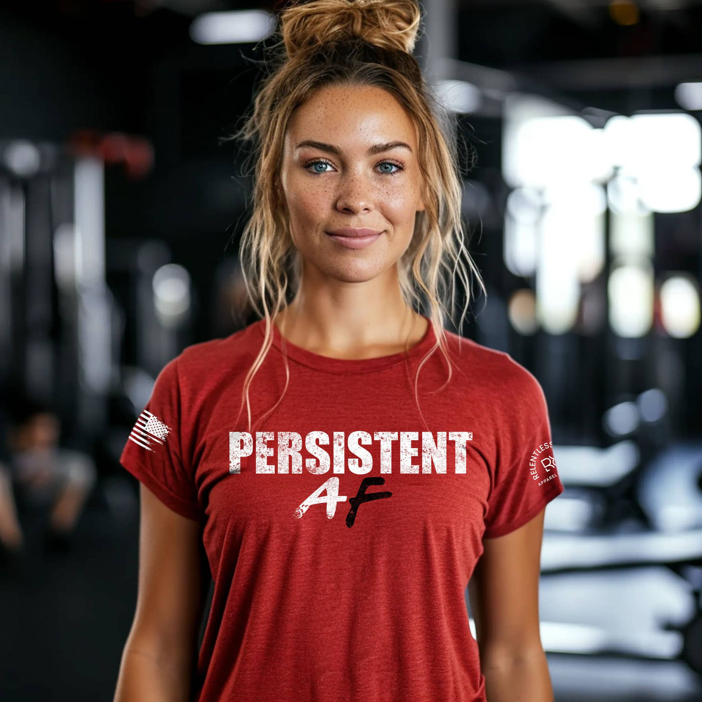 Woman wearing a red t-shirt with 'PERSISTENT AF' text in a gym setting