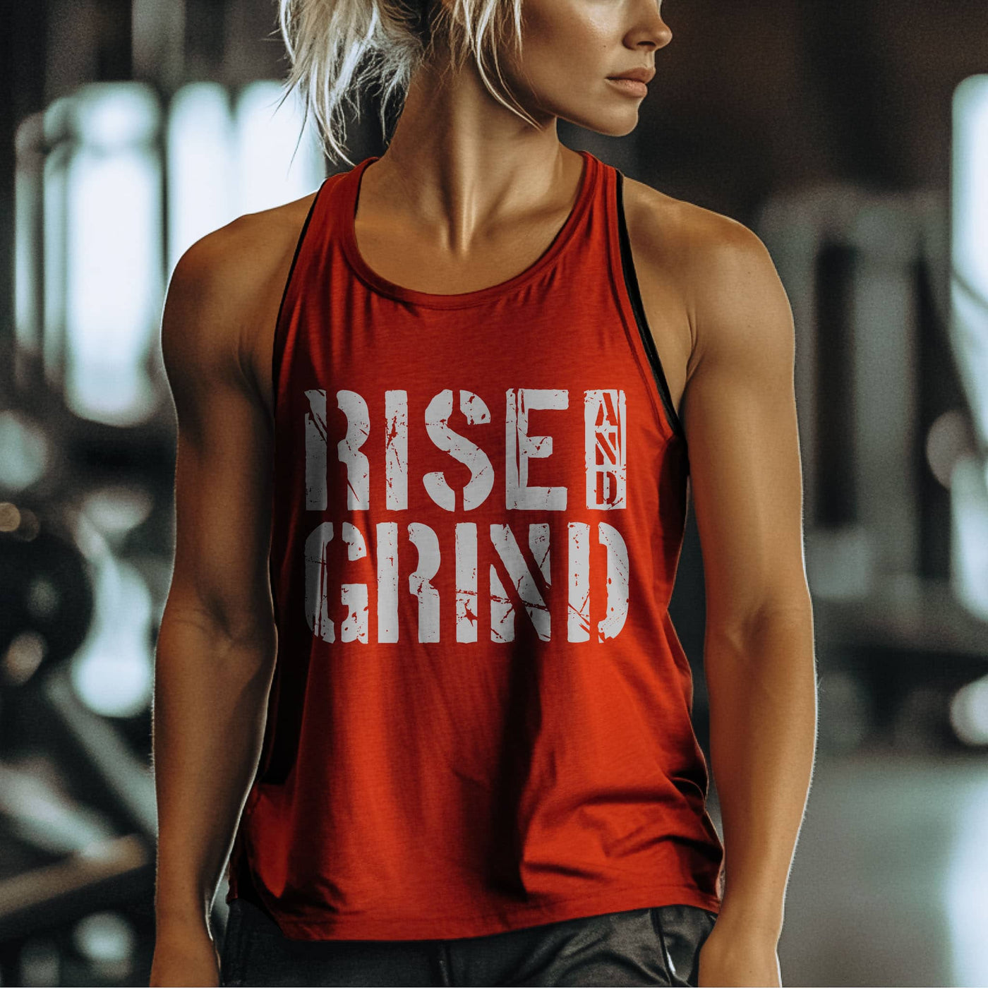 Person wearing a red tank top with 'RISE N GRIND' text in a gym setting
