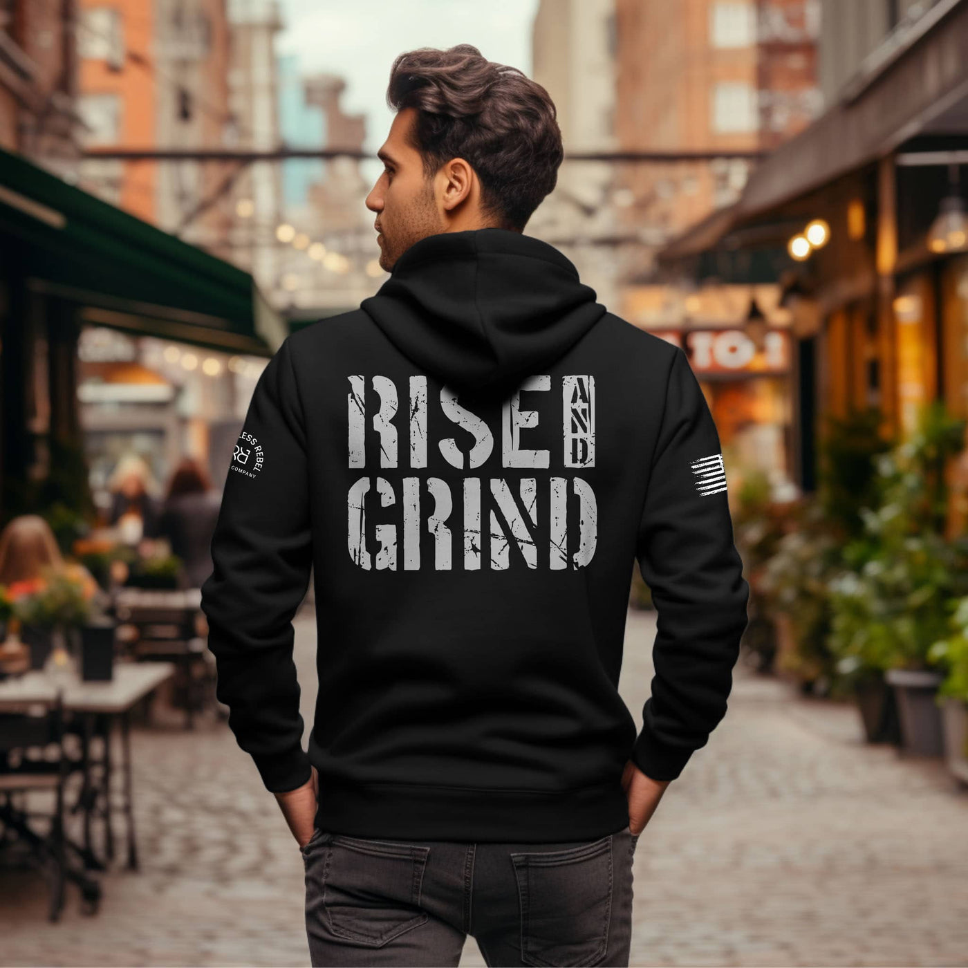 Man wearing a black zip-up hoodie with the words Rise and Grind on the back