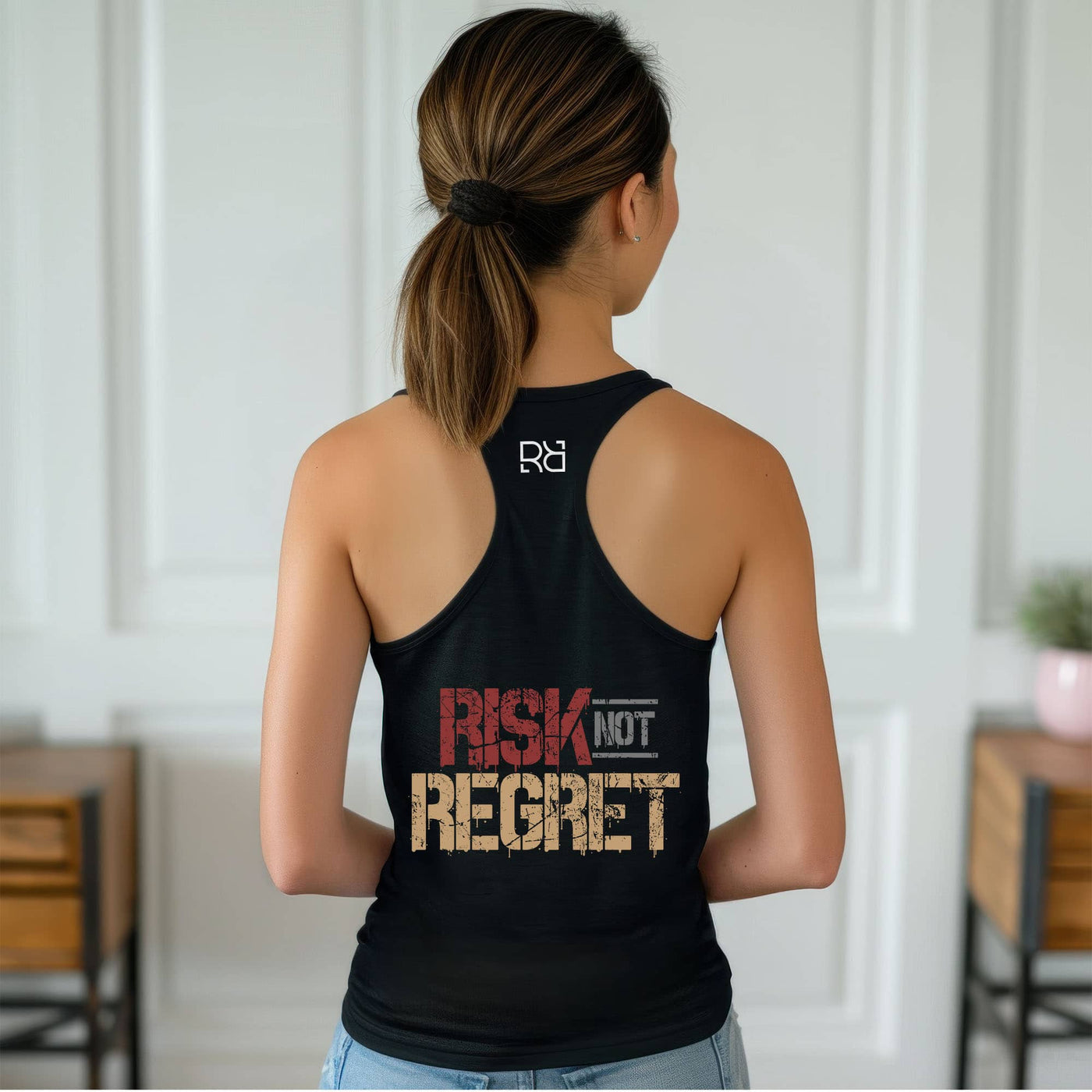 Person wearing a black tank top with 'Risk Not Regret' text and logo.