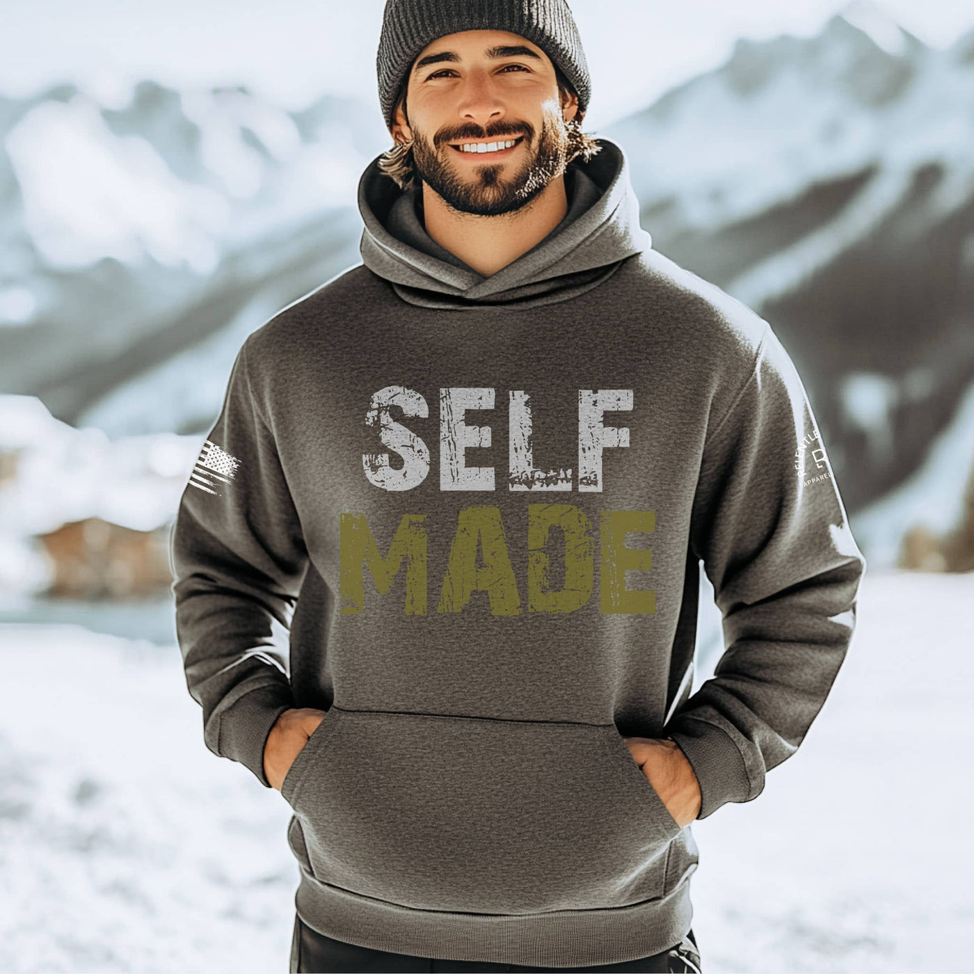 Man wearing a hoodie with 'SELF MADE' text in a snowy mountain setting