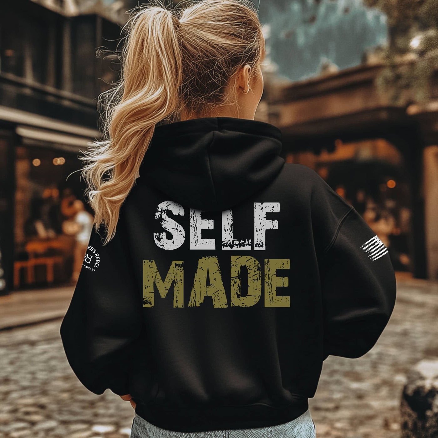 Person wearing a black hoodie with 'SELF MADE' text on the back, standing outdoors.