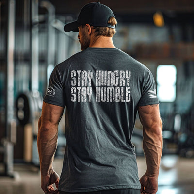 Man wearing a gray t-shirt with 'Stay Hungry Stay Humble' text in a gym setting