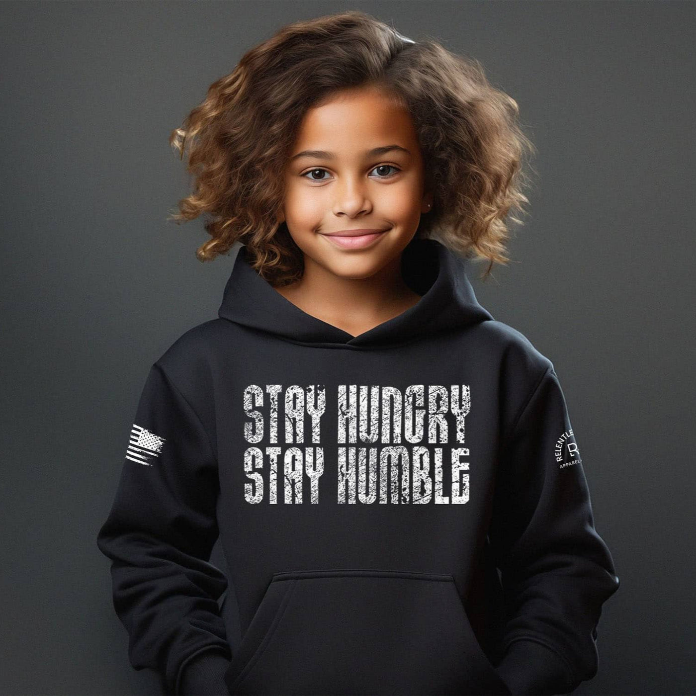 Child wearing a black hoodie with 'Stay Hungry Stay Humble' text on a dark background