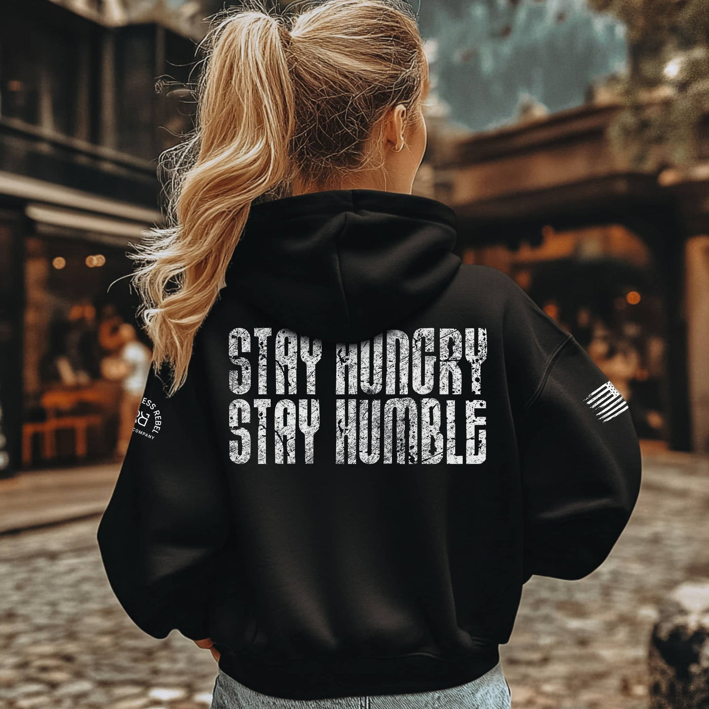 Person wearing a black hoodie with 'Stay Hungry Stay Humble' text on the back, standing outdoors.
