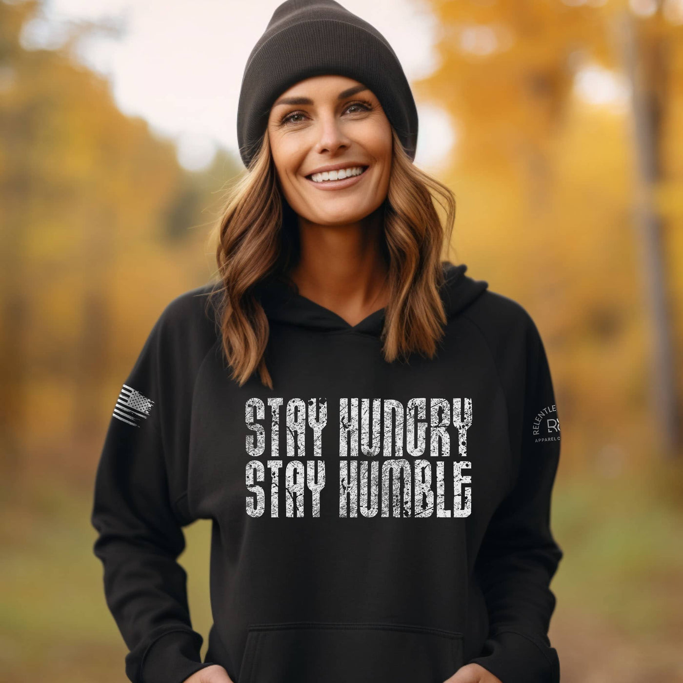 Woman wearing a black hoodie with 'Stay Hungry Stay Humble' text in an autumn setting