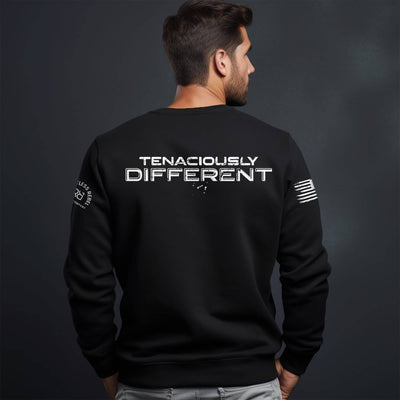 Man wearing a black sweatshirt with 'Tenaciously Different' text on the back against a dark background