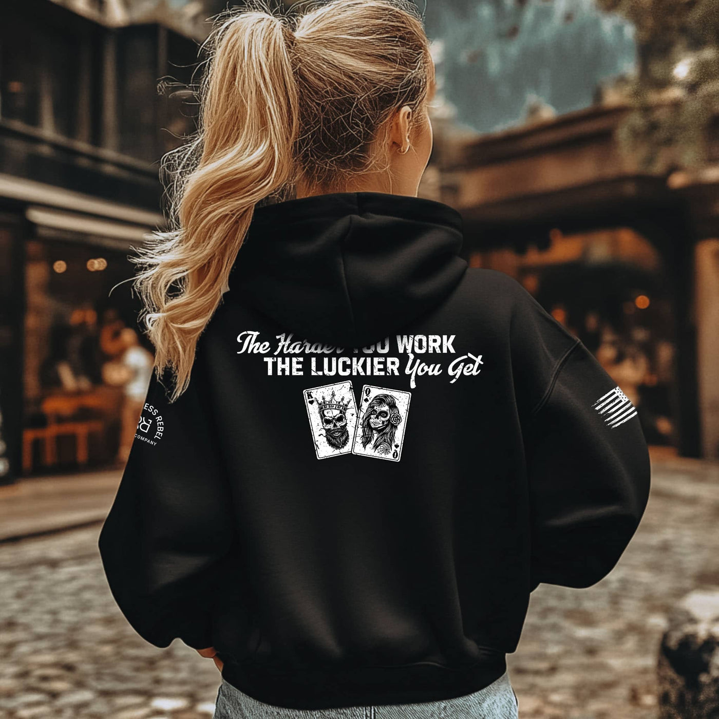 Person wearing a black hoodie with text and graphics on the back, standing outdoors.