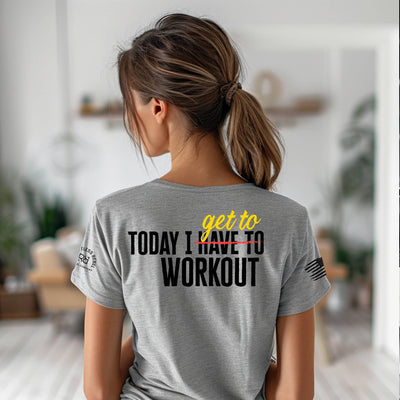 Person wearing a gray t-shirt with a motivational quote on the back in a home setting.