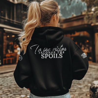 Person wearing a black hoodie with text on the back, standing outdoors.